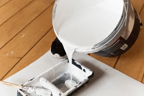 pouring white paint into bucket